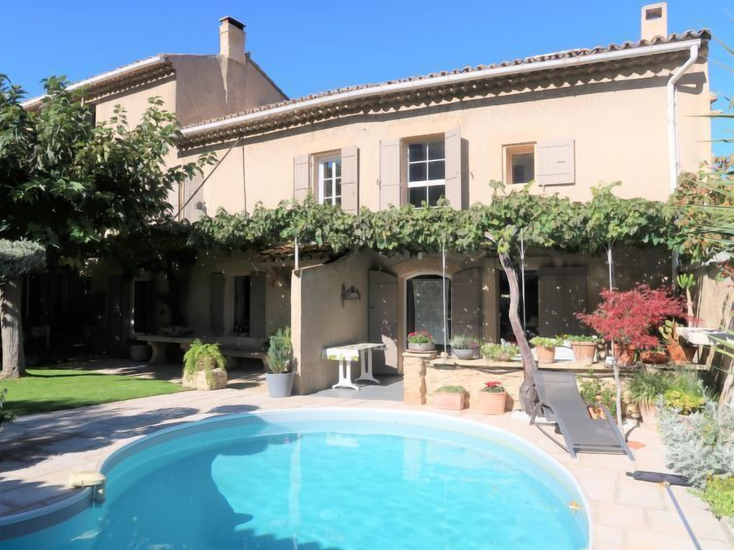 A house with a swimming pool, a garden, and a patio area.