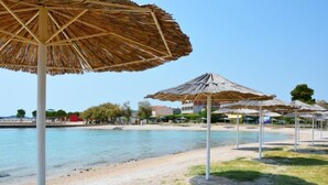 Una playa con sombrillas de paja y una vista despejada del mar.
