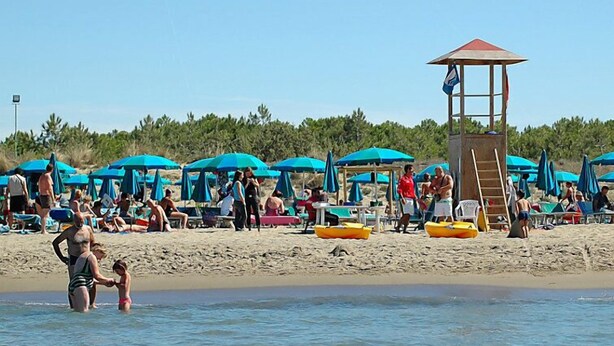 A beach with umbrellas, a lifeguard tower, and people enjoying the water. - Le Capanne I by Interhome (Grosseto)