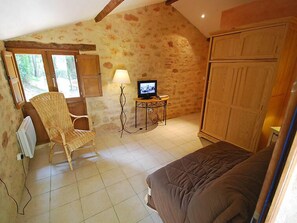A cozy room with a bed, a chair, a television, and a wardrobe.