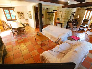 A spacious room with a dining area, two sofas, a small table, and a staircase leading to another level.