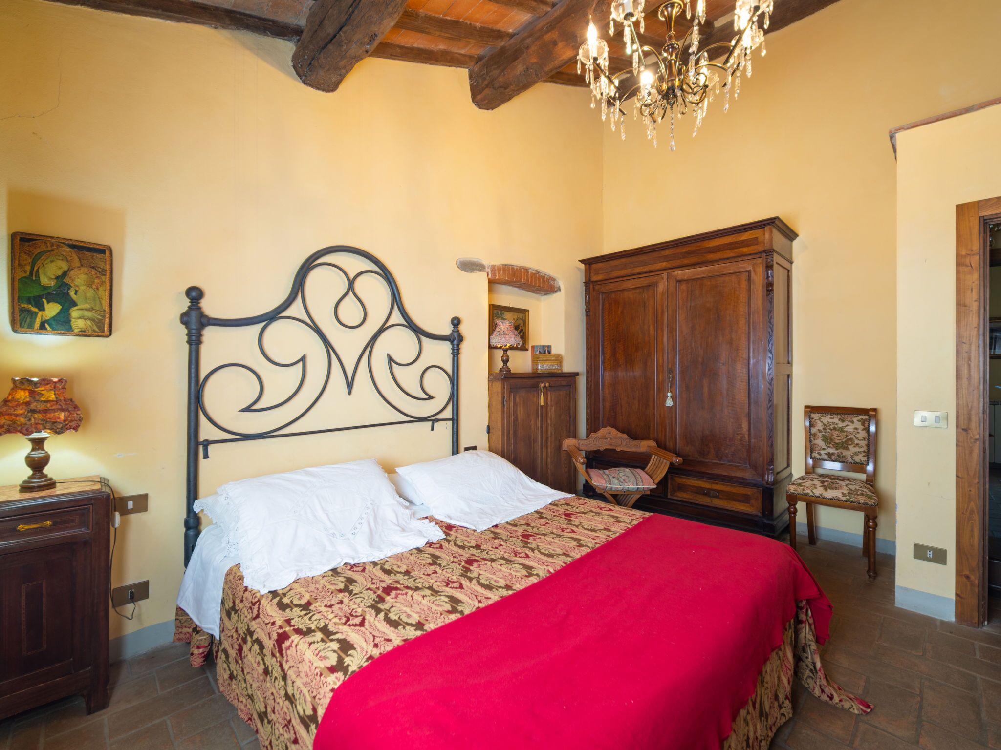 Une chambre à coucher avec un lit, une armoire en bois, une chaise et un lustre.