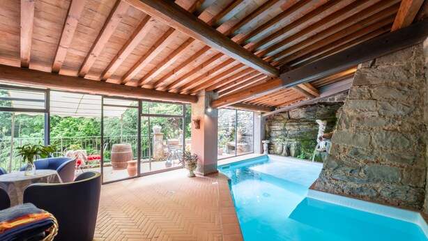 An indoor swimming pool with a stone wall, wooden ceiling beams, and a herringbone floor pattern. - Apartment Giallo by Interhome (Loro Ciuffenna)