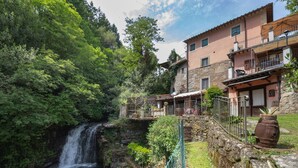 A rustic stone building with a balcony overlooking a waterfall. - Apartment Giallo by Interhome (Loro Ciuffenna)