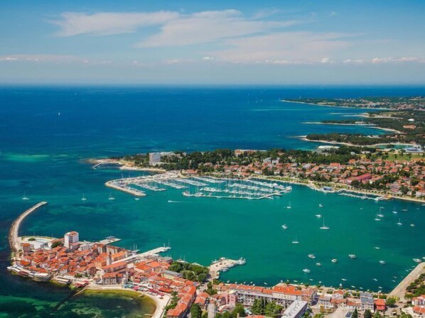 An aerial view of a coastal town with a marina, clear blue waters, and a mix of residential and commercial buildings.