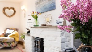 Ein Wohnzimmer mit Kamin, einer herzförmigen Dekoration und einem Blumenstrauß.