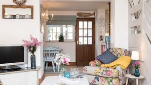 Ein gemütliches Wohnzimmer mit einer floralen Couch, einem Fernseher und einem Couchtisch mit Zeitschriften.