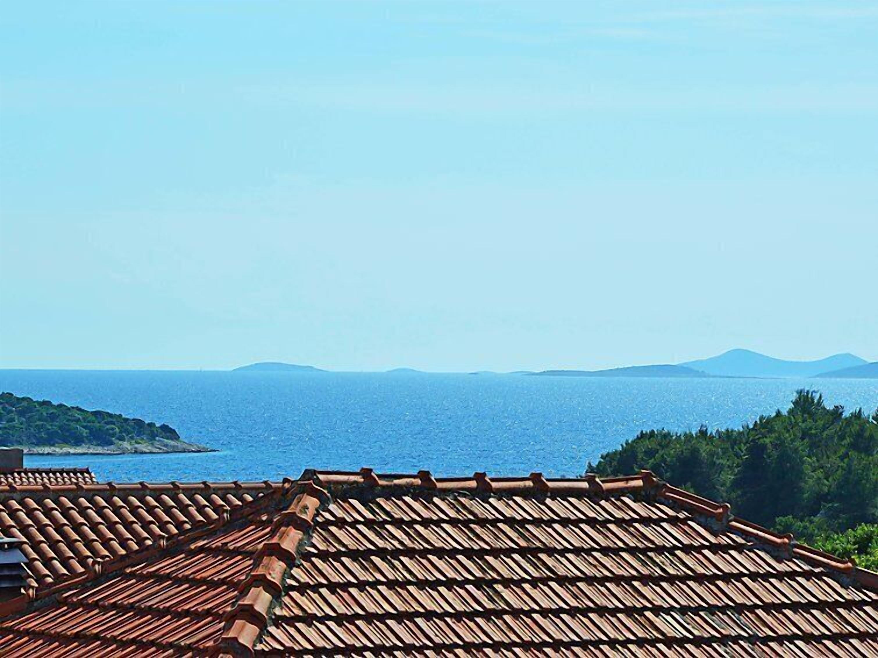A coastal view with a tiled roof and a clear sky.