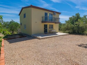 A two-story building with a balcony, a small patio, and a gravel driveway. - Vacation home Tea by Interhome (Pašman/Nevidane)