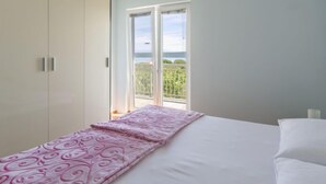A bedroom with a bed, a wardrobe, and a balcony with a view. - Vacation home Tea by Interhome (Pašman/Nevidane)