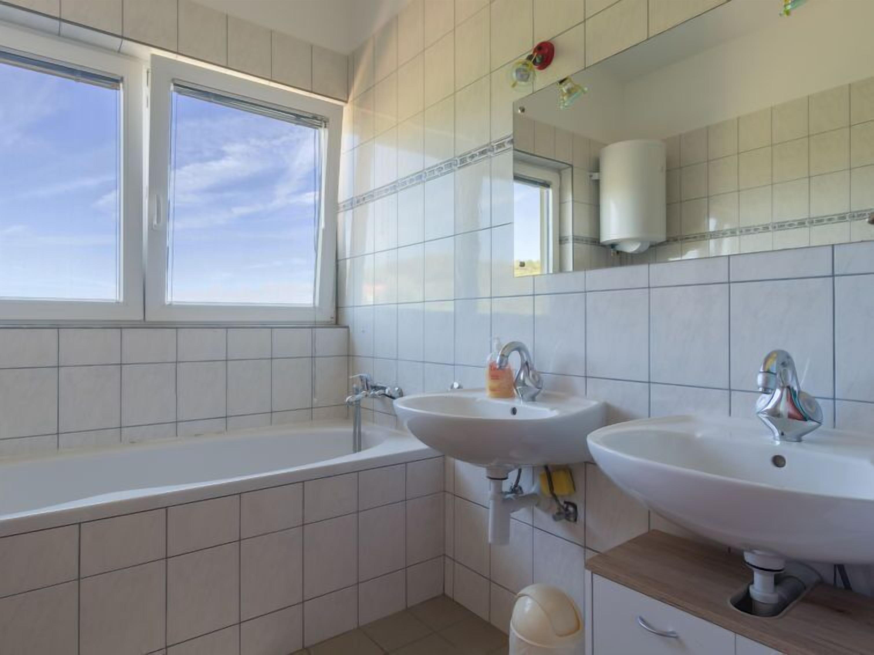 Une salle de bain avec deux lavabos, une baignoire et une fenêtre.
