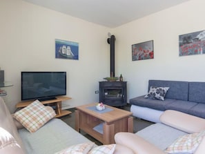 A living room with a sofa, a television, a fireplace, and artwork on the walls.
