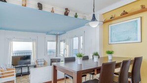 A dining area with a wooden table and chairs, potted plants, and a large painting on the wall. - Joan Sarda by Interhome (Roses)