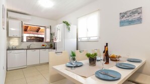 Una cocina moderna con armarios blancos, horno empotrado y comedor con mesa lista para dos.