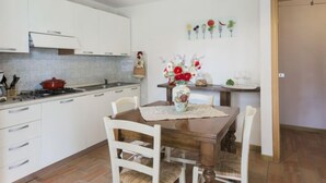 Una cocina moderna con armarios blancos, una mesa de comedor de madera y una lámpara colgante.