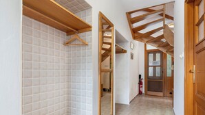 Un pasillo con un banco de madera, paredes enlosadas y una puerta de madera.