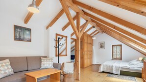Un dormitorio acogedor en el ático, con techo de madera, un sofá, una cama y una pequeña mesa.