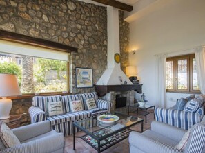 A cozy living room with a stone wall, a fireplace, striped sofas, and a glass coffee table.