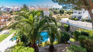 A residential area with a swimming pool surrounded by lush greenery and palm trees. - Els Jardins III by Interhome (Roses)