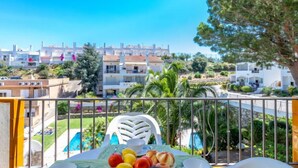 A balcony with a table set for breakfast, overlooking a pool and residential buildings. - Els Jardins III by Interhome (Roses)