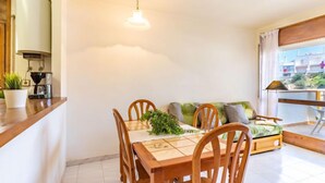 A dining area with a wooden table, chairs, and a ceiling light. - Els Jardins III by Interhome (Roses)