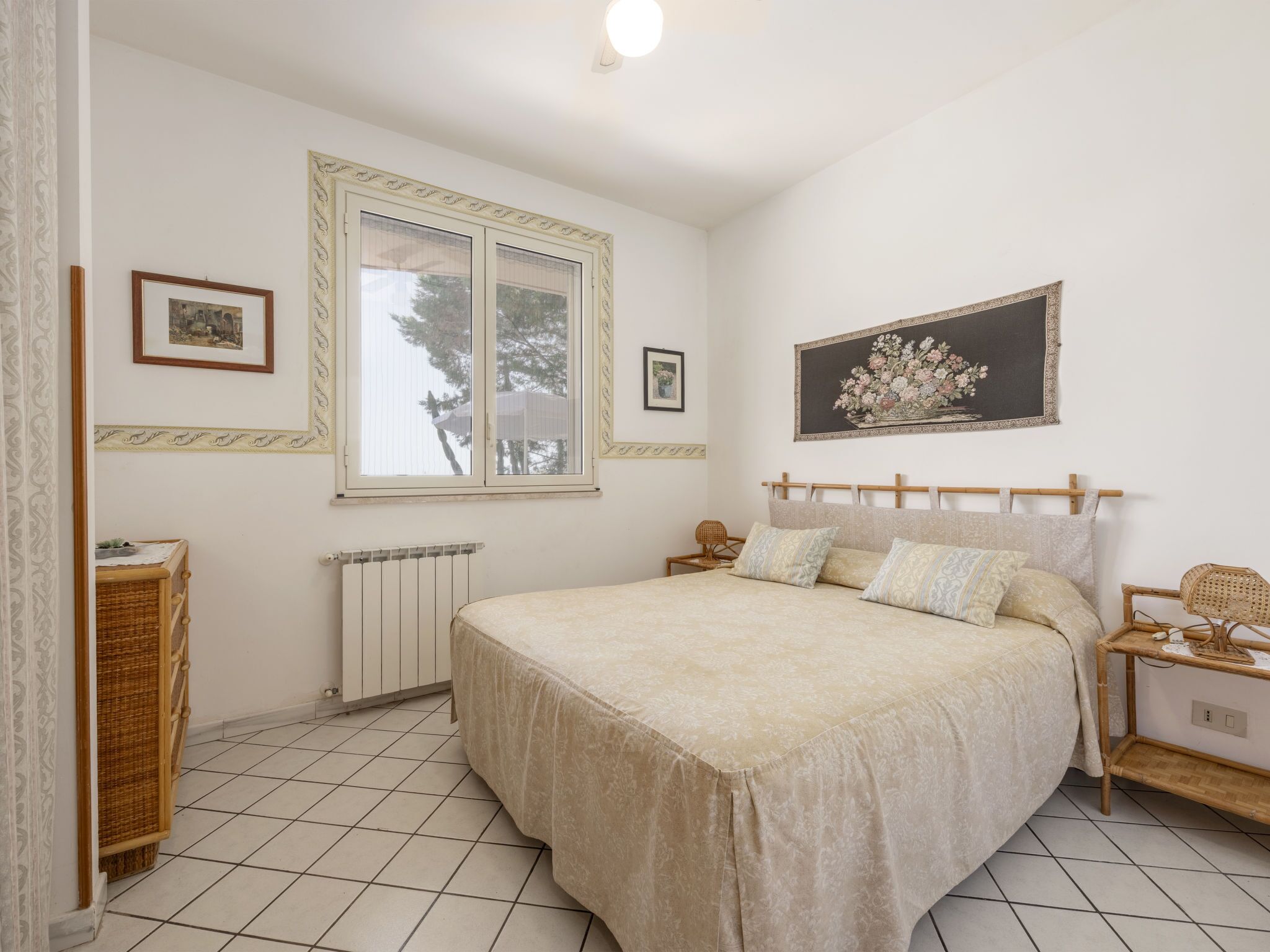Une chambre à coucher avec un lit, un radiateur, une fenêtre et un tableau encadré accroché au mur.