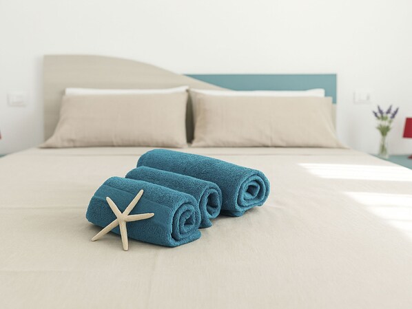 A neatly made bed with blue towels and a starfish decoration.