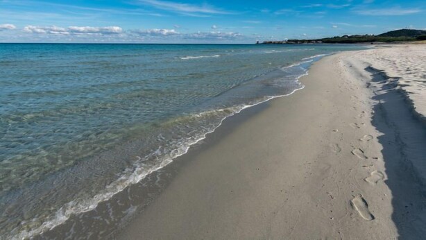 A beach with clear water, a sandy shore, and footprints. - Bellina by Interhome (La Caletta)
