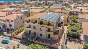 A residential area with terracotta-roofed buildings, a solar panel on one house, and a clear view of the sea in the background. - Bellina by Interhome (La Caletta)