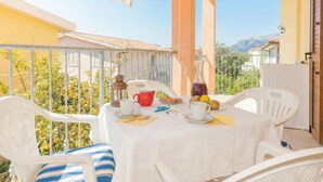 A balcony with a table set for two, chairs, a red kettle, and a bottle of red wine. - Bellina by Interhome (La Caletta)