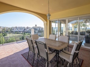 Varanda com mesa e cadeiras, vista para a cidade e guarda-corpo.