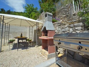 A barbecue grill and a covered dining area with a table and chairs. - Šverko 2 by Interhome (Trget)