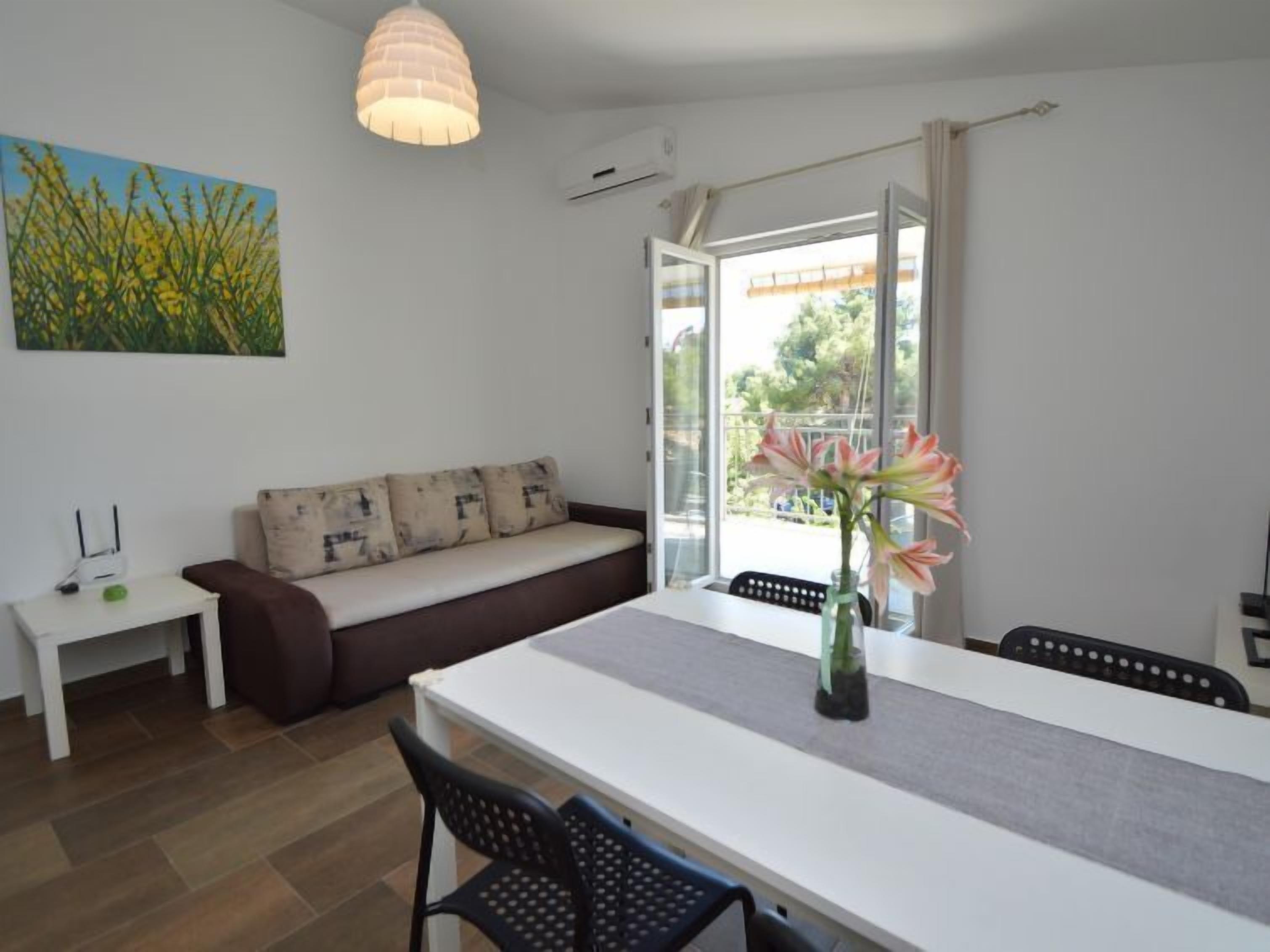 Una sala moderna con un sofá blanco, una mesa de comedor y un ventanal grande.