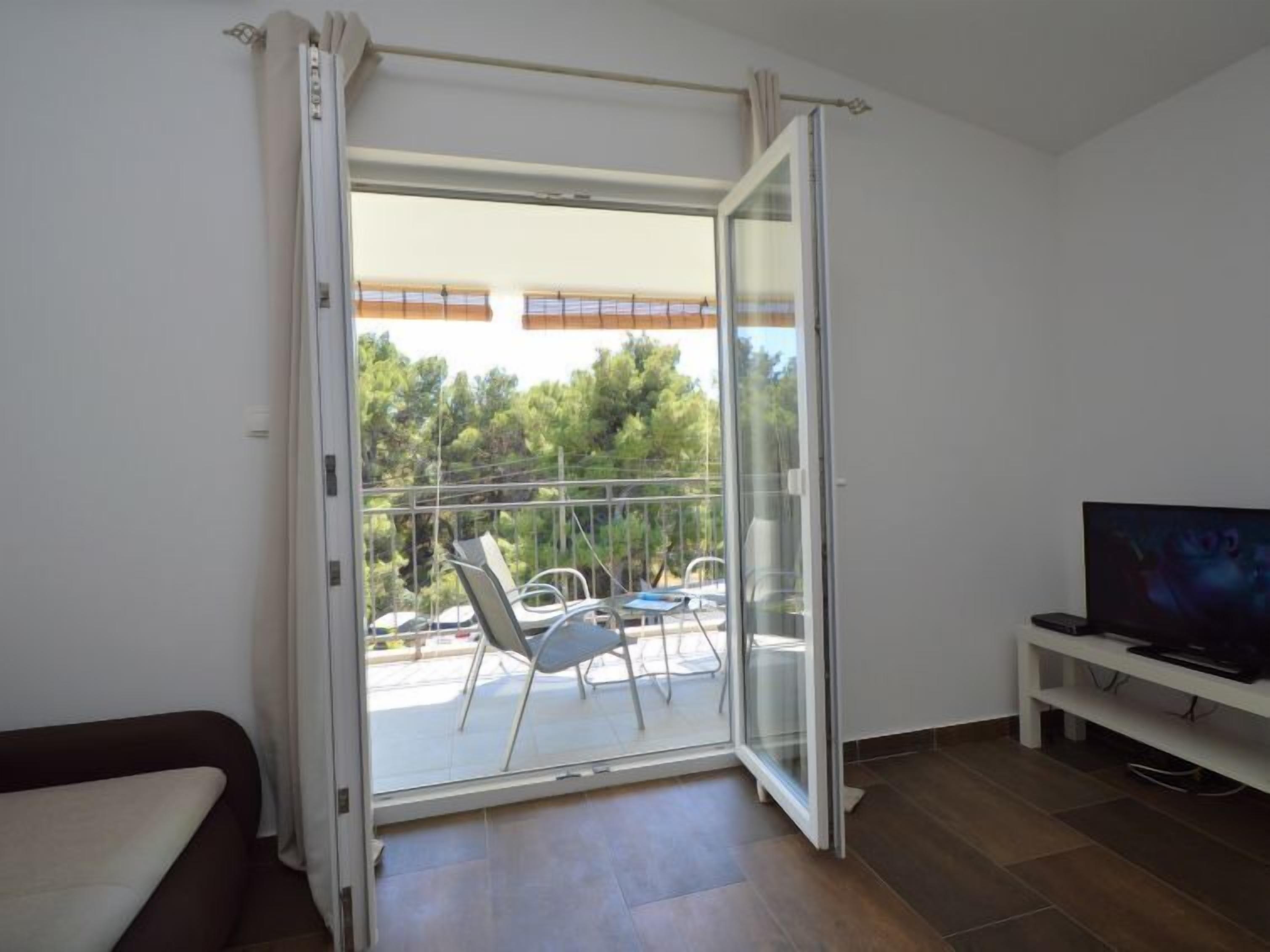 A room with a sliding glass door leading to an outdoor balcony with a table and chairs.