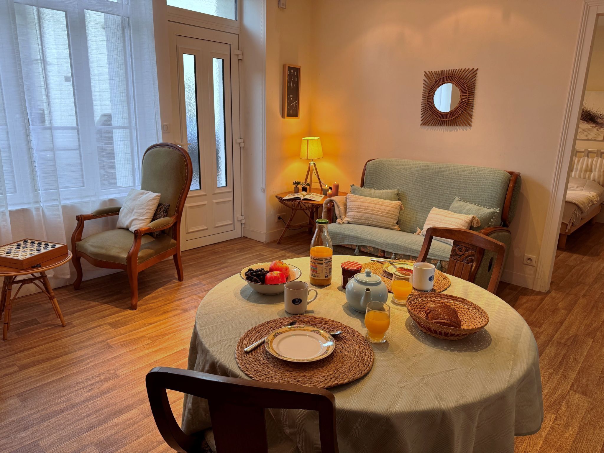 A cozy dining area with a table set for breakfast, a sofa, and a chair.