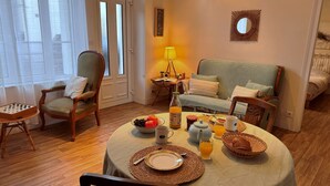Uma área de jantar acolhedora com uma mesa posta para o café da manhã, um sofá e uma cadeira.