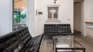 Una sala de estar moderna con un sofá de cuero negro, una mesa de centro de vidrio y un ventanal con vistas a la vegetación.