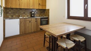 A kitchen with wooden cabinets, a coffee maker, and a window. - Resort al Centro by Interhome (Breganzona)
