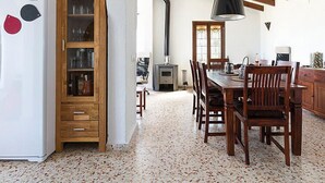 A dining area with a wooden table and chairs, a built-in cabinet, and a kitchen area with a stove and refrigerator.