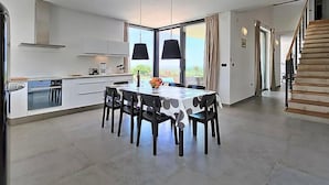 Uma cozinha moderna com área de refeições, janelas amplas e uma escada.
