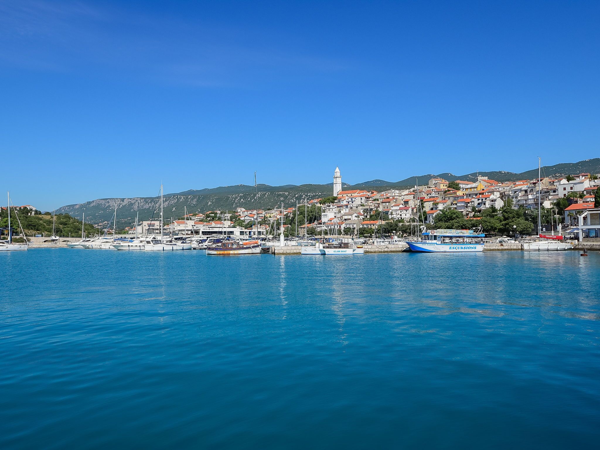 A coastal town with a marina, boats, and a prominent tower.