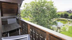 A wooden balcony with a view of a garden and pond. - Schnitzer by Interhome (Seeboden)