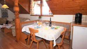A cozy dining area with a wooden table set for four, surrounded by wooden chairs. A small refrigerator is visible to the right. - Schnitzer by Interhome (Seeboden)