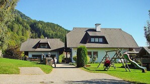 A two-story building with a sloped roof, a front entrance, and a small porch area. - Schnitzer by Interhome (Seeboden)