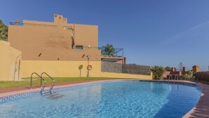 A clear swimming pool with a tiled edge, a metal ladder, and a lifebuoy. In the background, there is a building with a flat roof and a balcony. - Vistamar by Interhome (Torredembarra)