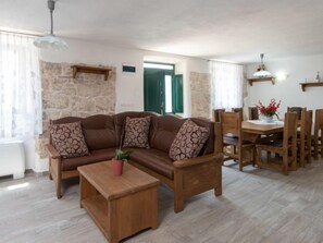 A cozy living room with a brown leather sofa, a wooden coffee table, and a dining area with wooden chairs and a table.