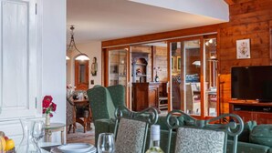 A dining area with a table set for two, chairs, and a television in the background. - Belle Vue by Interhome (Nendaz)