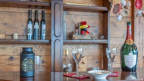 A wooden bar area with bottles of wine, a bottle of champagne, and glasses on the counter. - Belle Vue by Interhome (Nendaz)