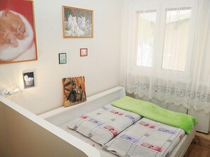 A bedroom with a bed, a window with white curtains, and several framed pictures on the wall. - Vacation home Olešná by Interhome (Bernartice)