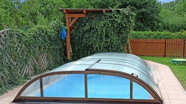 Een kasconstructie met een gebogen glazen dak en houten draagbalken.